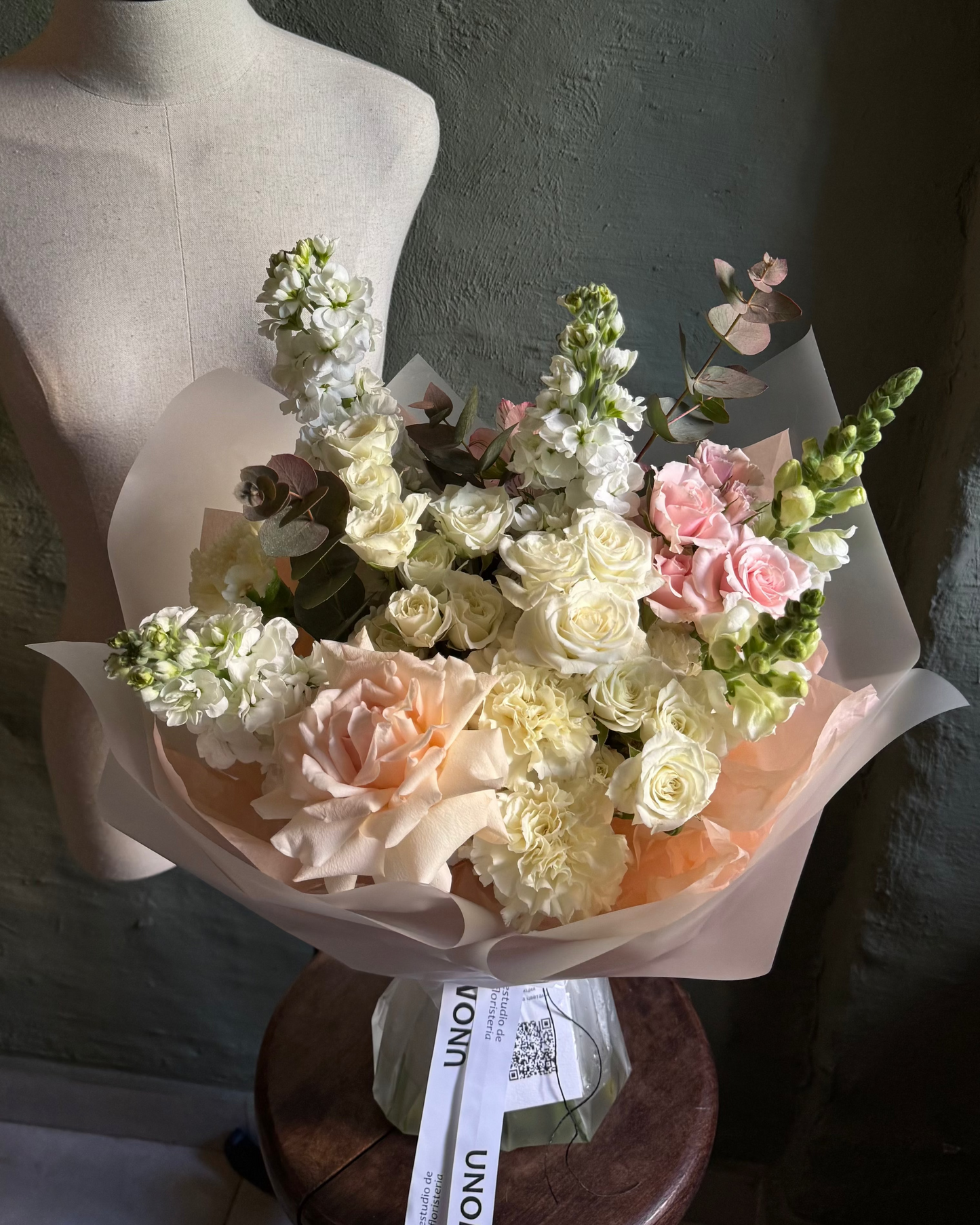 Bouquet of gentle flowers on a mannequin bust against a plain background