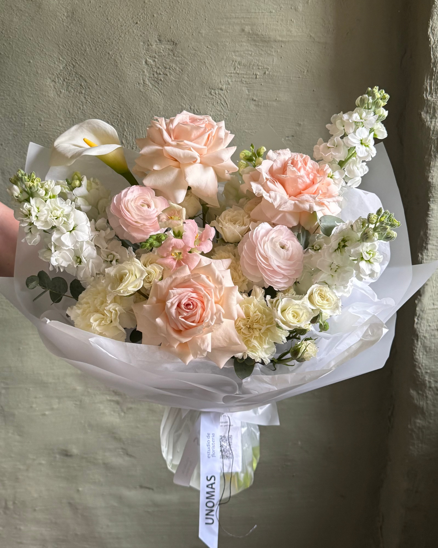 Bouquet of pink and white flowers wrapped in paper against a neutral background