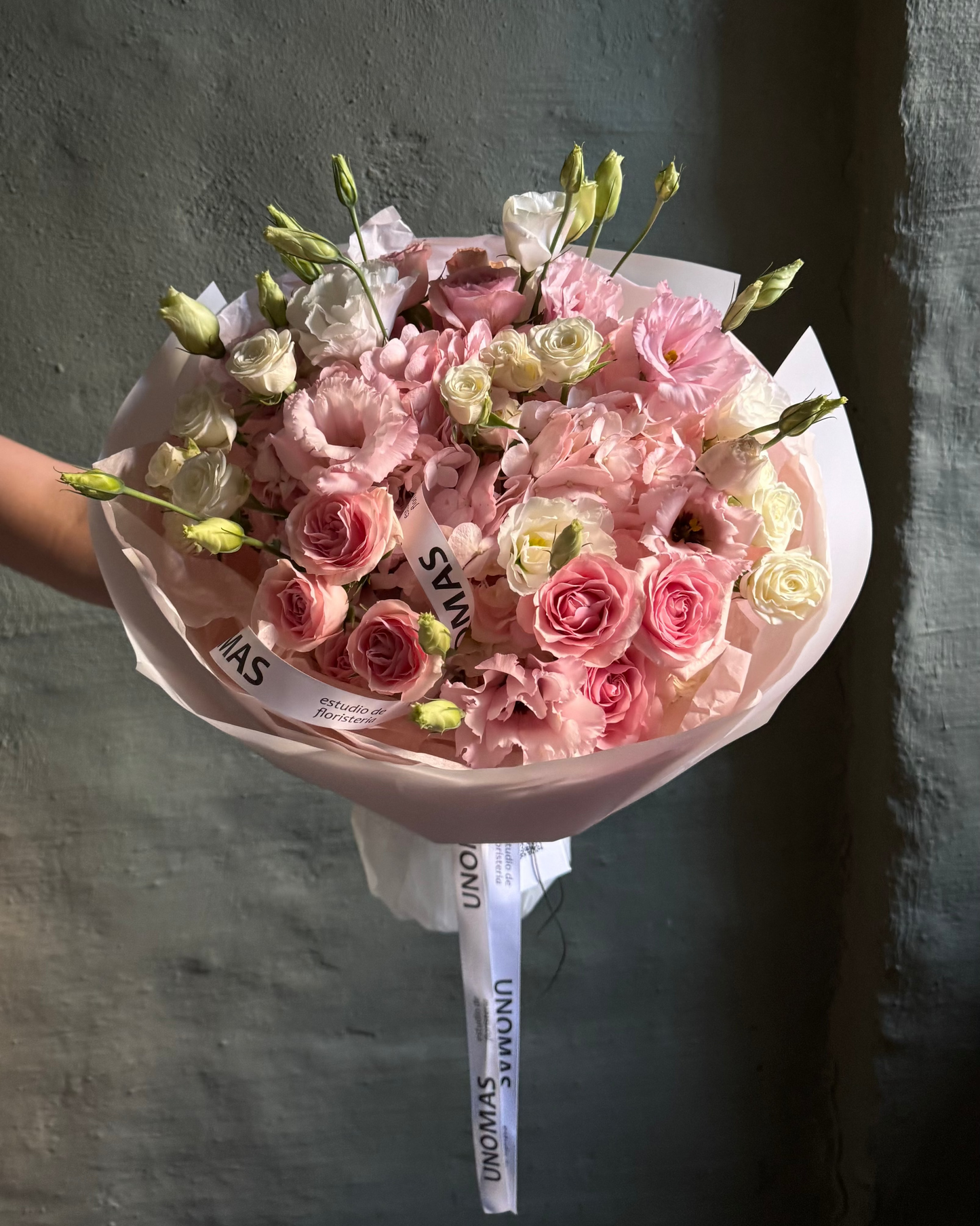 Bouquet of pink and white flowers with a visible brand label against a dark background