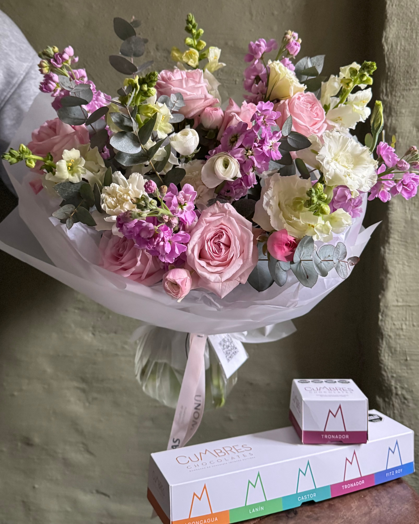 Bouquet of flowers with a box of chocolate on a wooden surface