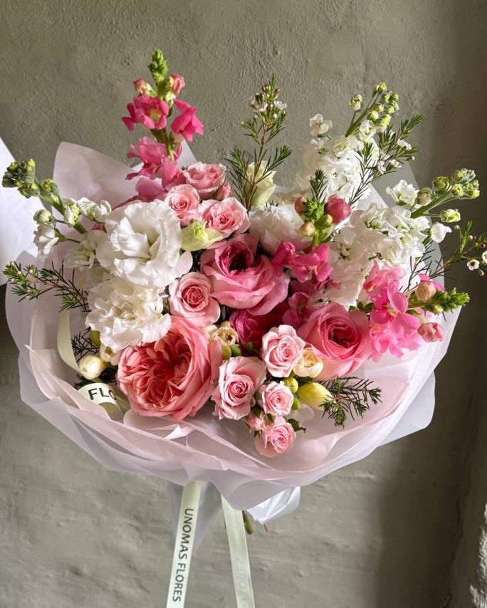 Ramo de rosas rosadas, rosas spray y flores blancas con eucalipto, envuelto en papel rosa claro.