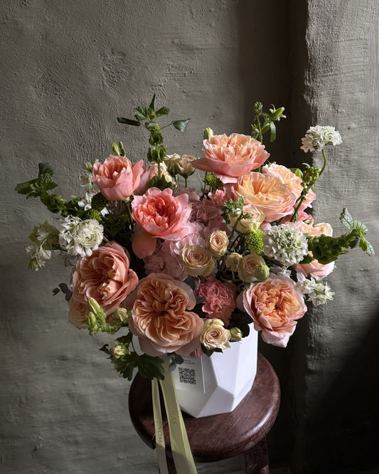 A large floral arrangement of peach, pink, cream, and white flowers with green foliage