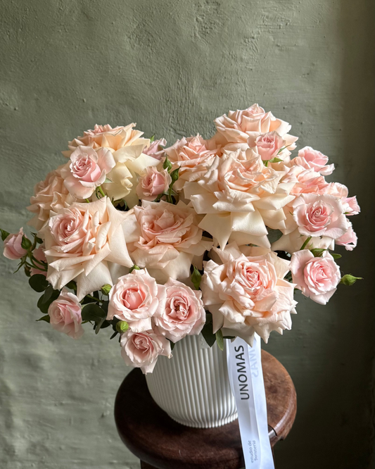 Arreglo floral mediano de rosas ecuatorianas y rosas spray en delicados tonos durazno, presentado en un cachepot blanco de Unomas Flores.