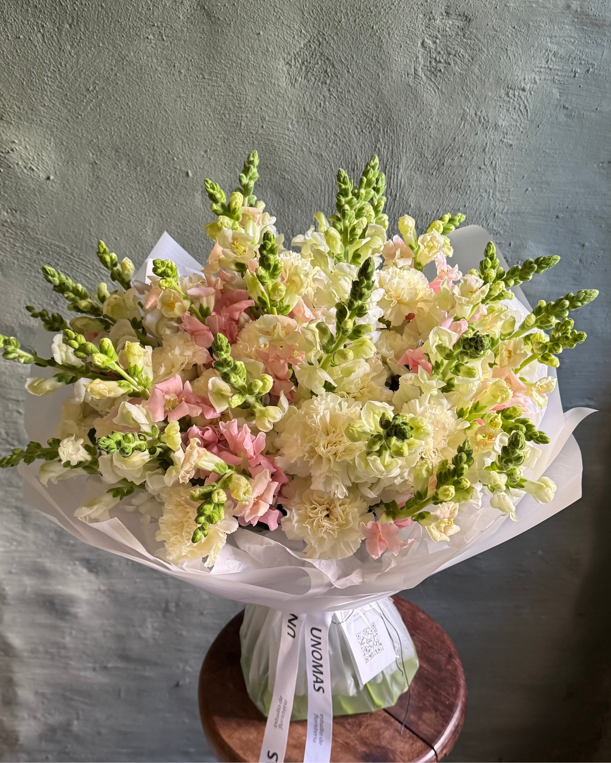Bouquet of flowers on a wooden stool against a plain wall