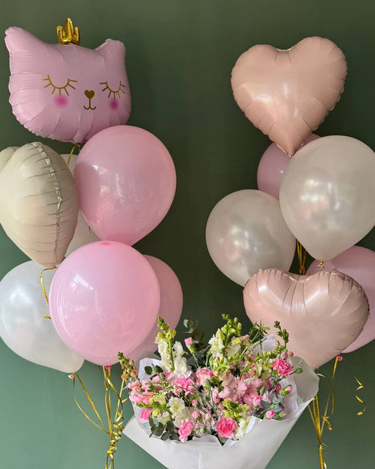 Bouquet of flowers with pink heart-shaped balloons against a green wall