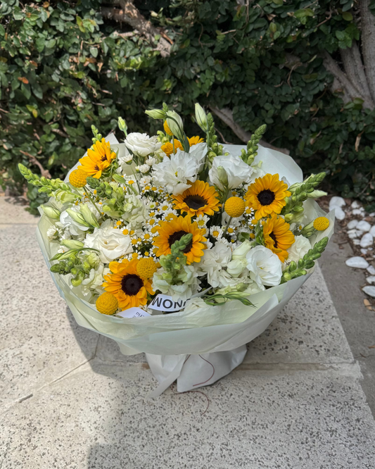 Bouquet of flowers with sunflowers and white flowers on a stone surface.