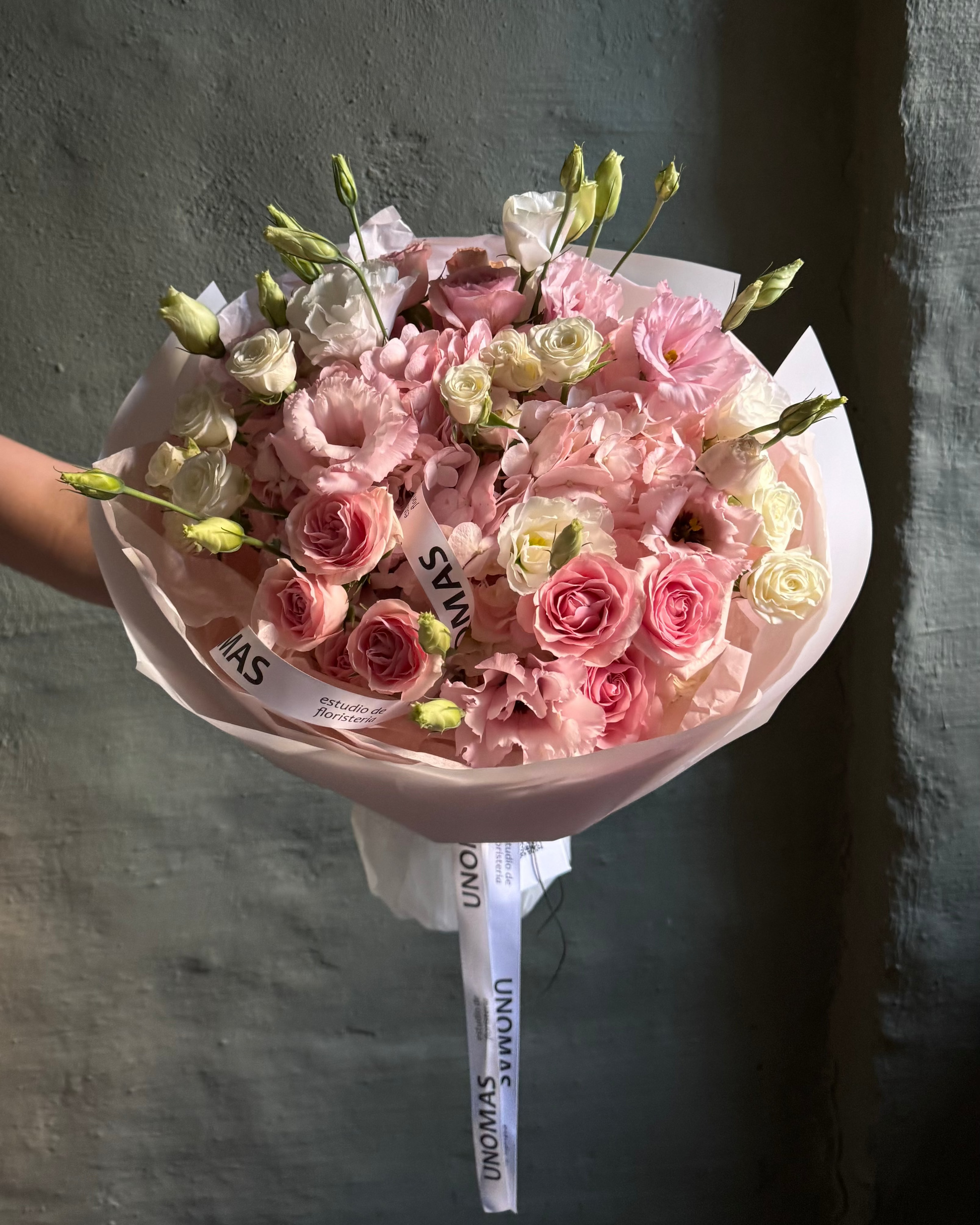 Bouquet of pink and white flowers with a visible brand label against a dark background