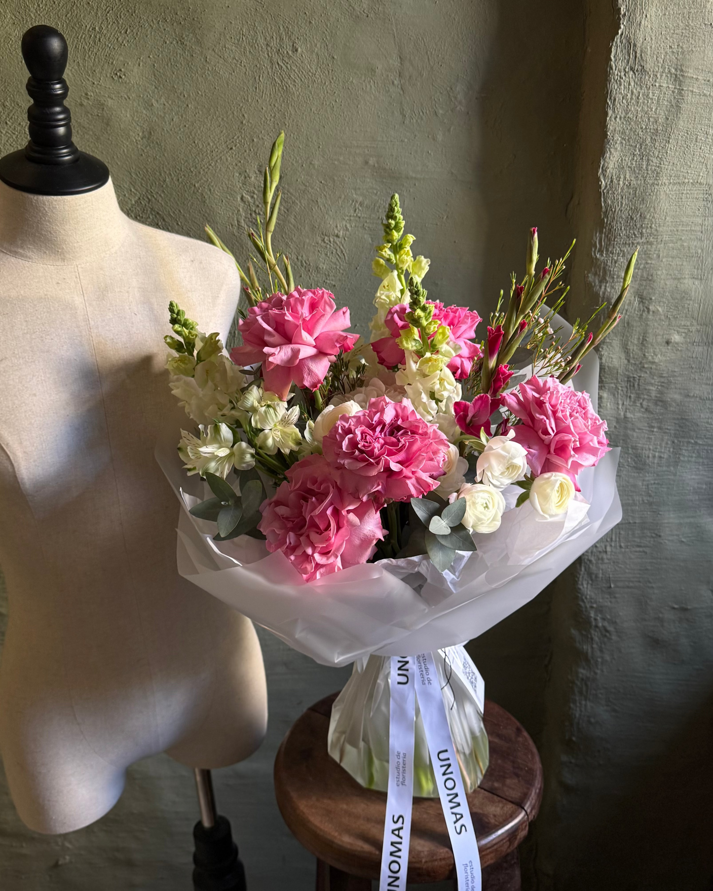 Bouquet of pink and white flowers on a mannequin bust against a neutral background