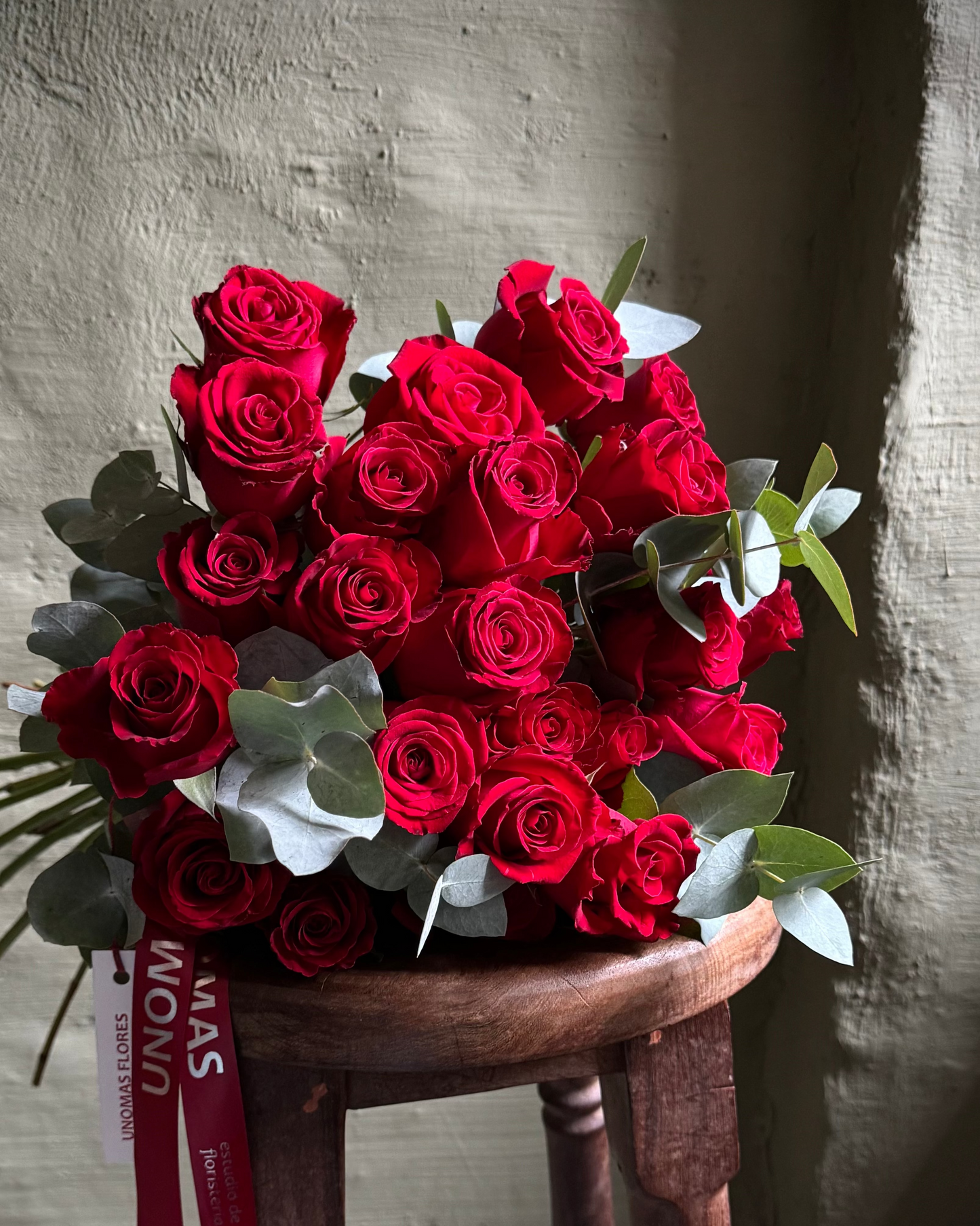 Bouquet of red roses on a wooden stool with a neutral background