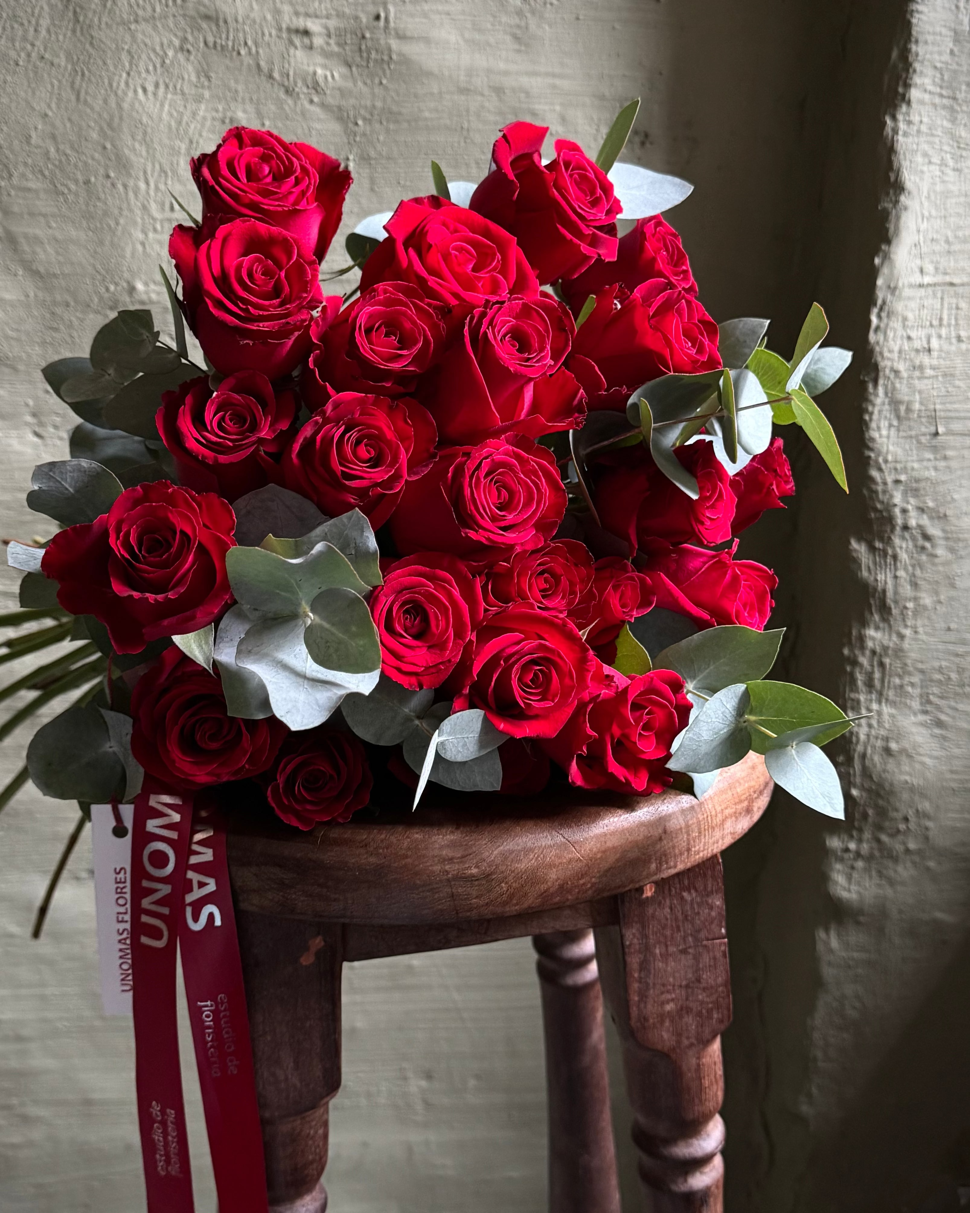 Bouquet of red roses on a wooden stool with a textured wall background