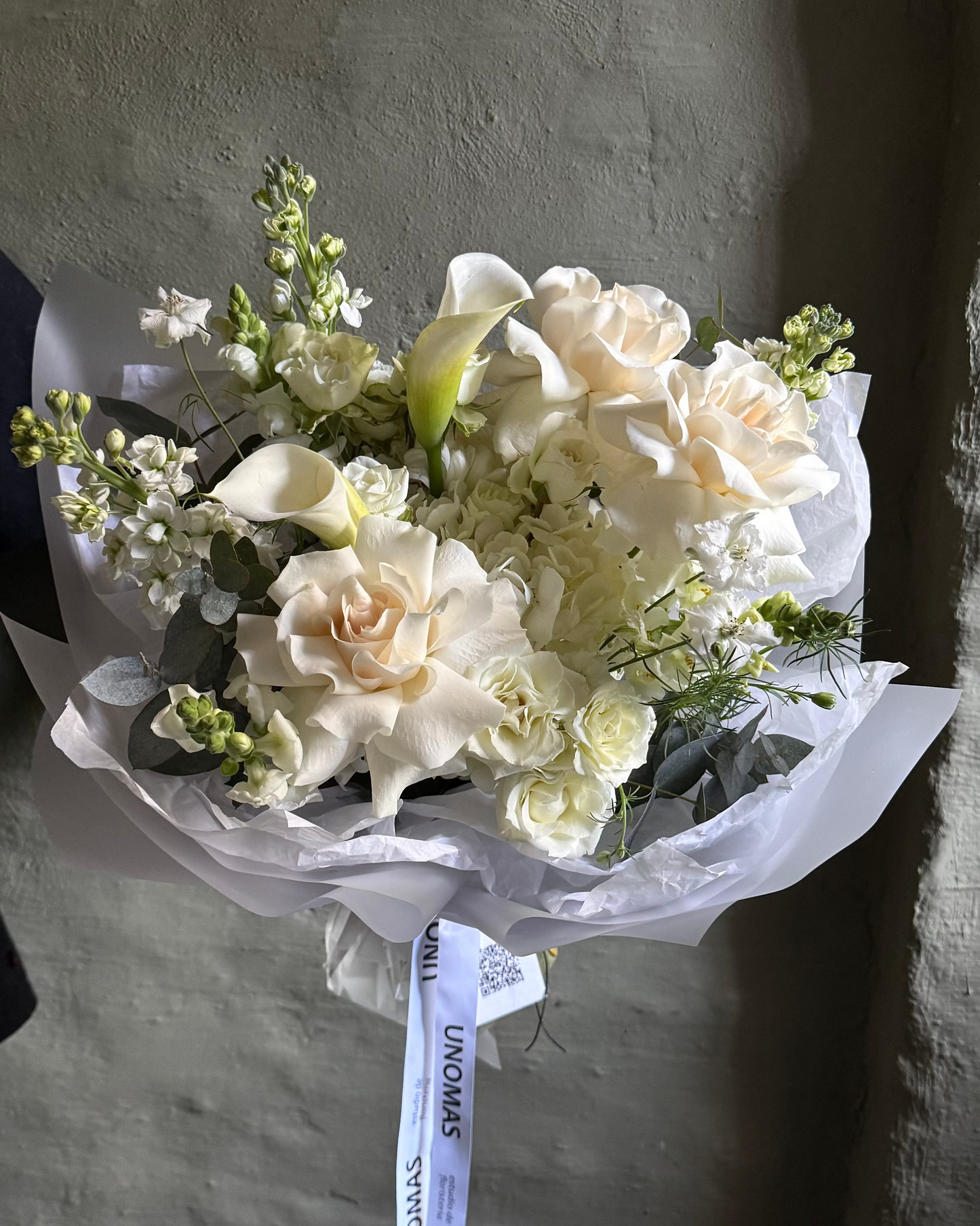 Bouquet of white flowers with greenery on a textured gray background