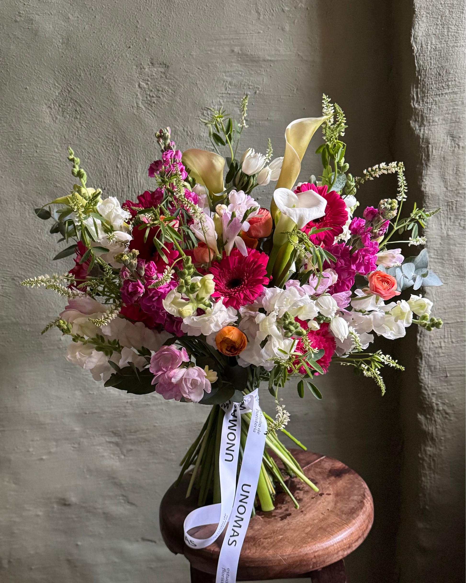 Bouquet of flowers on a wooden stool against a textured wall