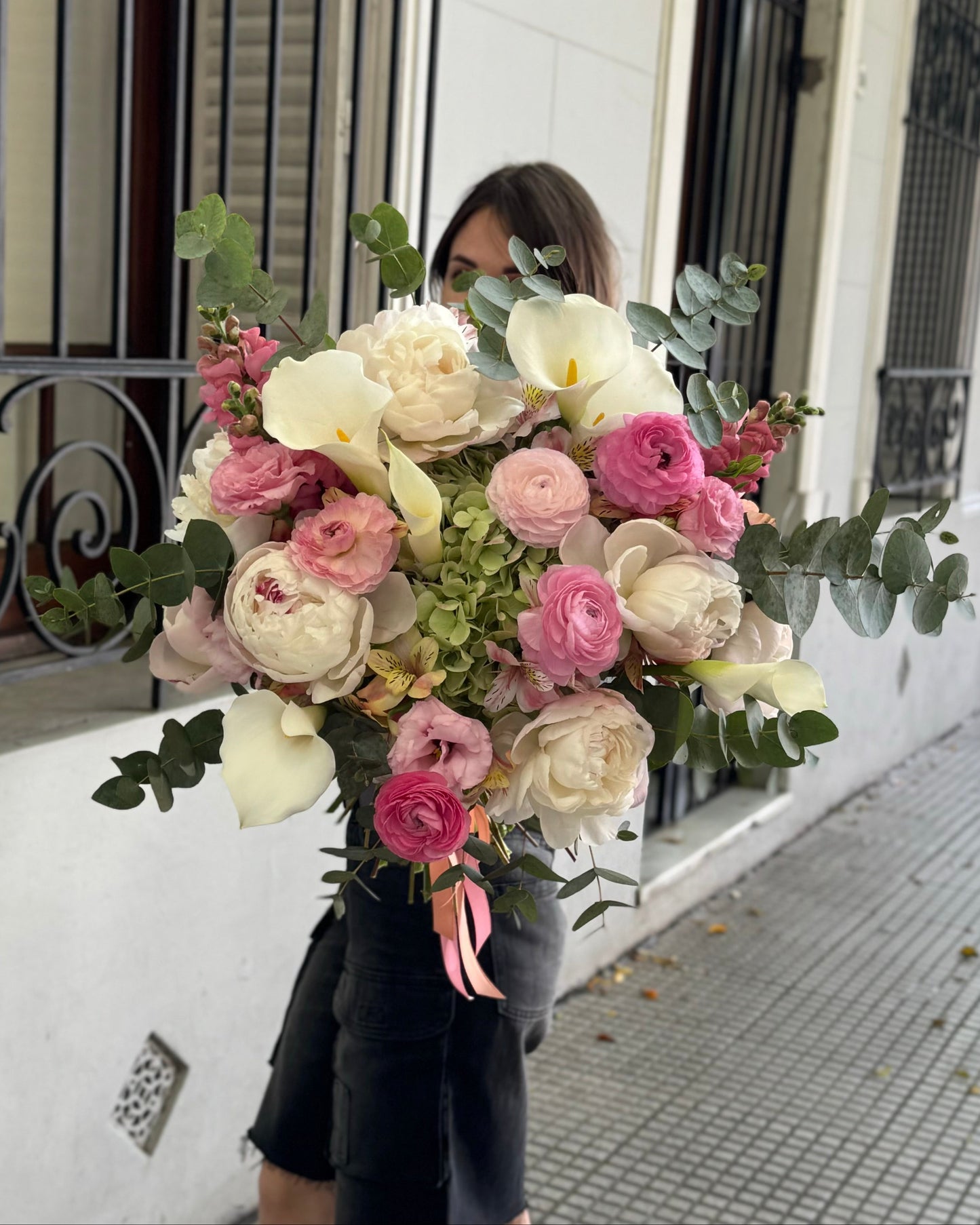 Person holding a large bouquet of flowers in an urban setting