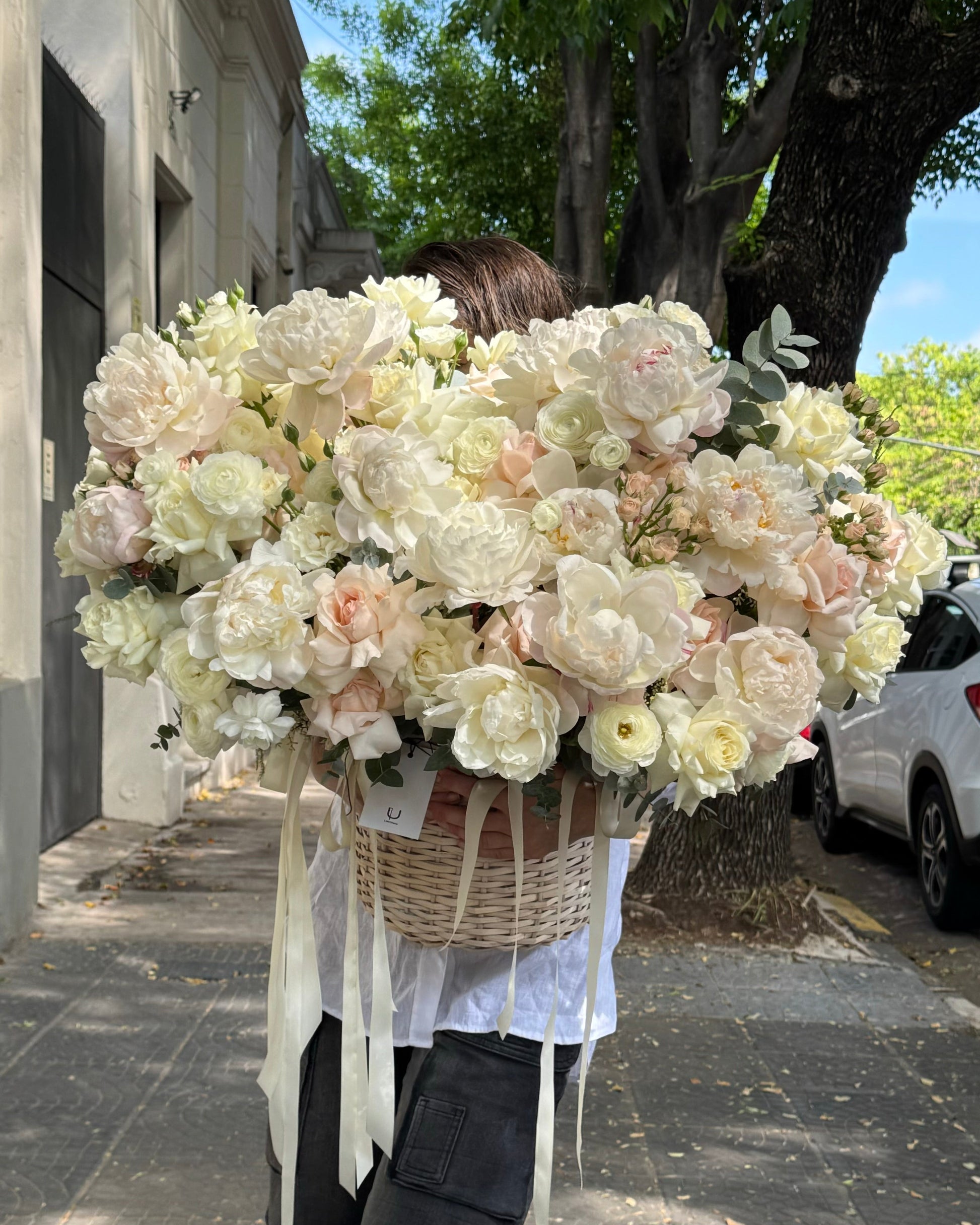 Person holding a large bouquet of flowers outdoors on a sunny day.