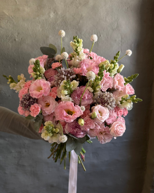 Bouquet of pink and white flowers held against a neutral background