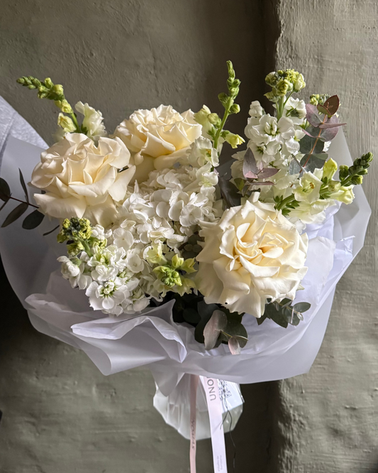 Bouquet of white flowers with greenery on a textured wall background