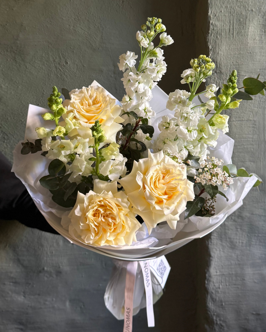Bouquet of yellow and white flowers held against a gray wall