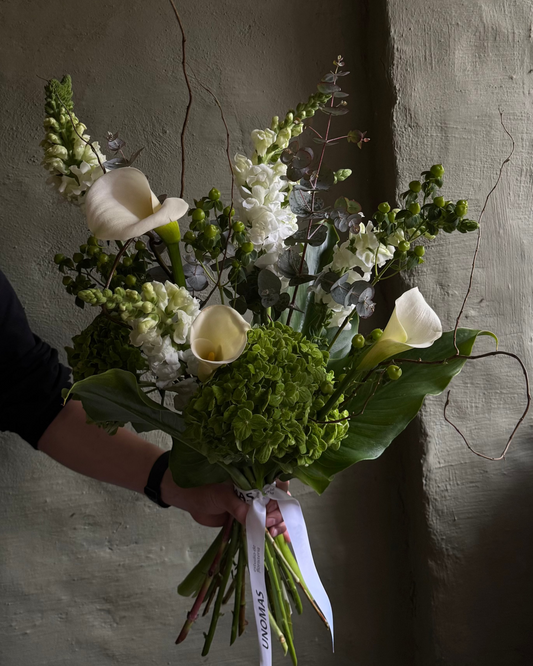 Men bouquet of green flowers held against a textured wall