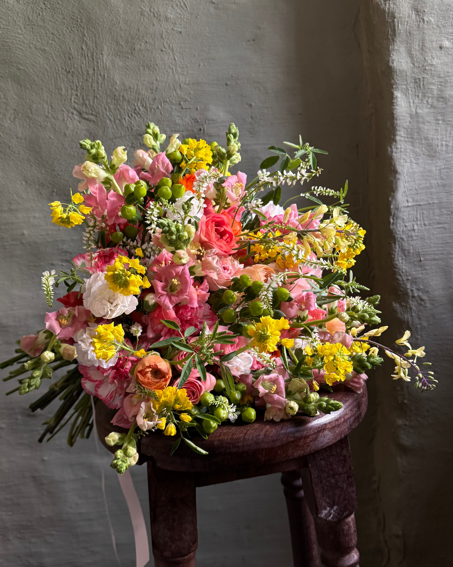 Bouquet of flowers on a wooden stool against a gray wall