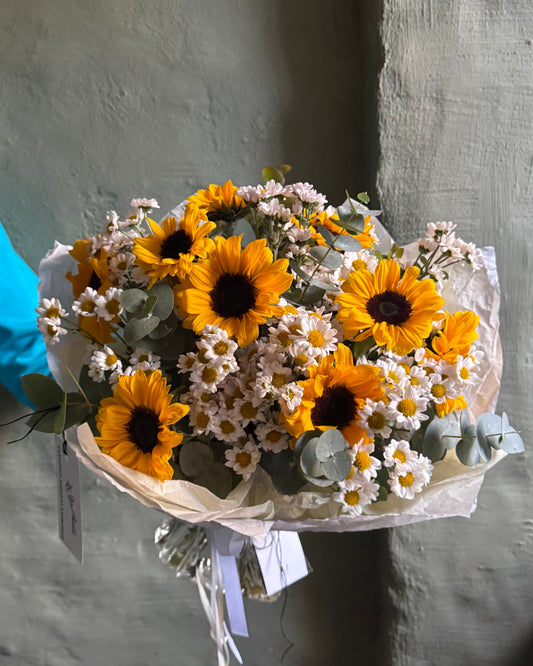 Bouquet of sunflowers and white flowers on a gray background
