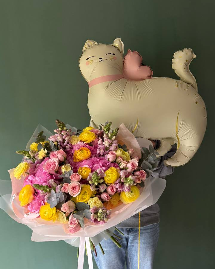 Person holding a bouquet of flowers and a balloon shaped like a cat with a pink bow against a green background