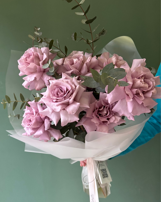 Un ramo de 7 rosas ecuatorianas lila suave con eucalipto en papel mate de Unomas Flores
