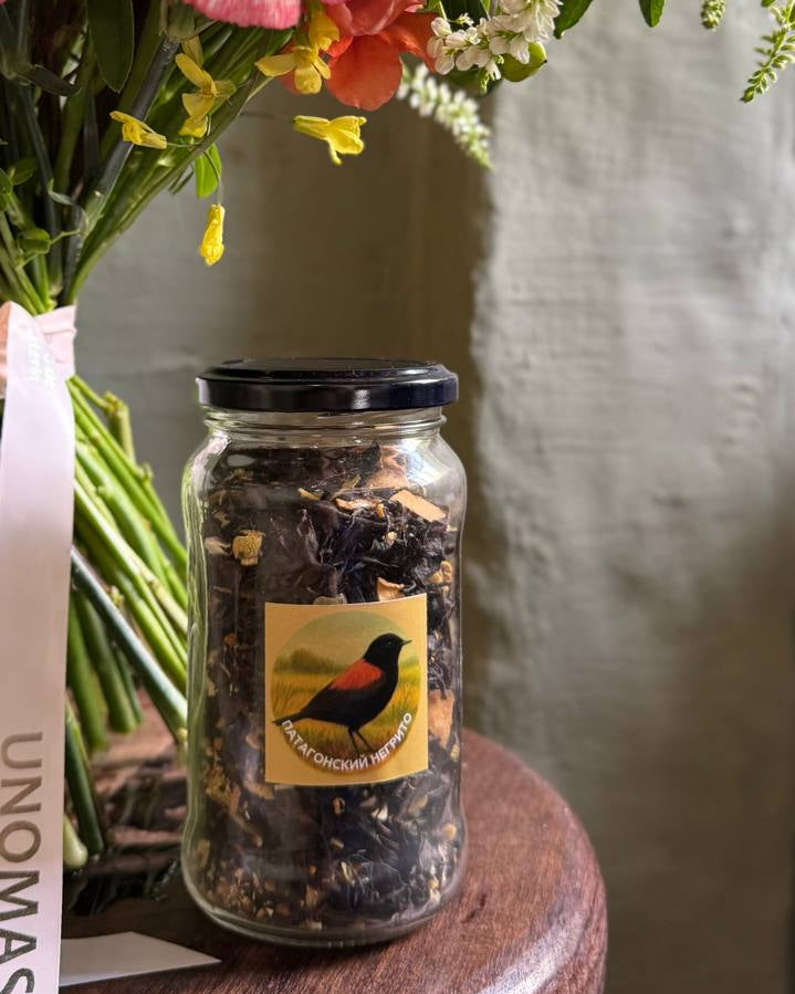 Jar of dried flowers with a label on a wooden surface next to a bouquet of flowers.
