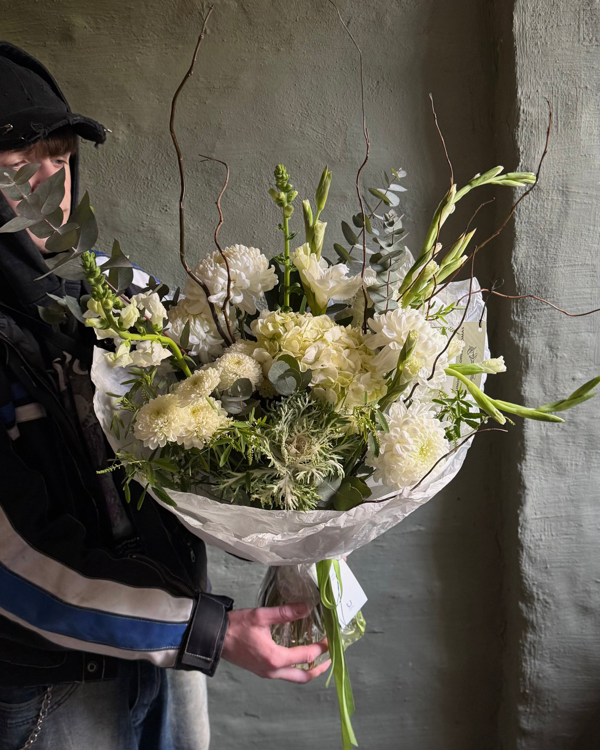 Bouquet of flowers ( hydrangea, brassica, chrusanthemums) a wooden stool against a textured wall