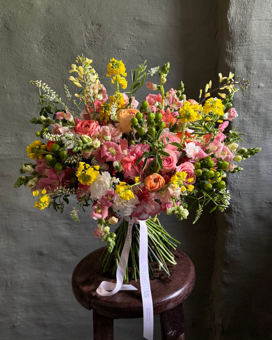 Bouquet of flowers on a wooden stool against a gray wall