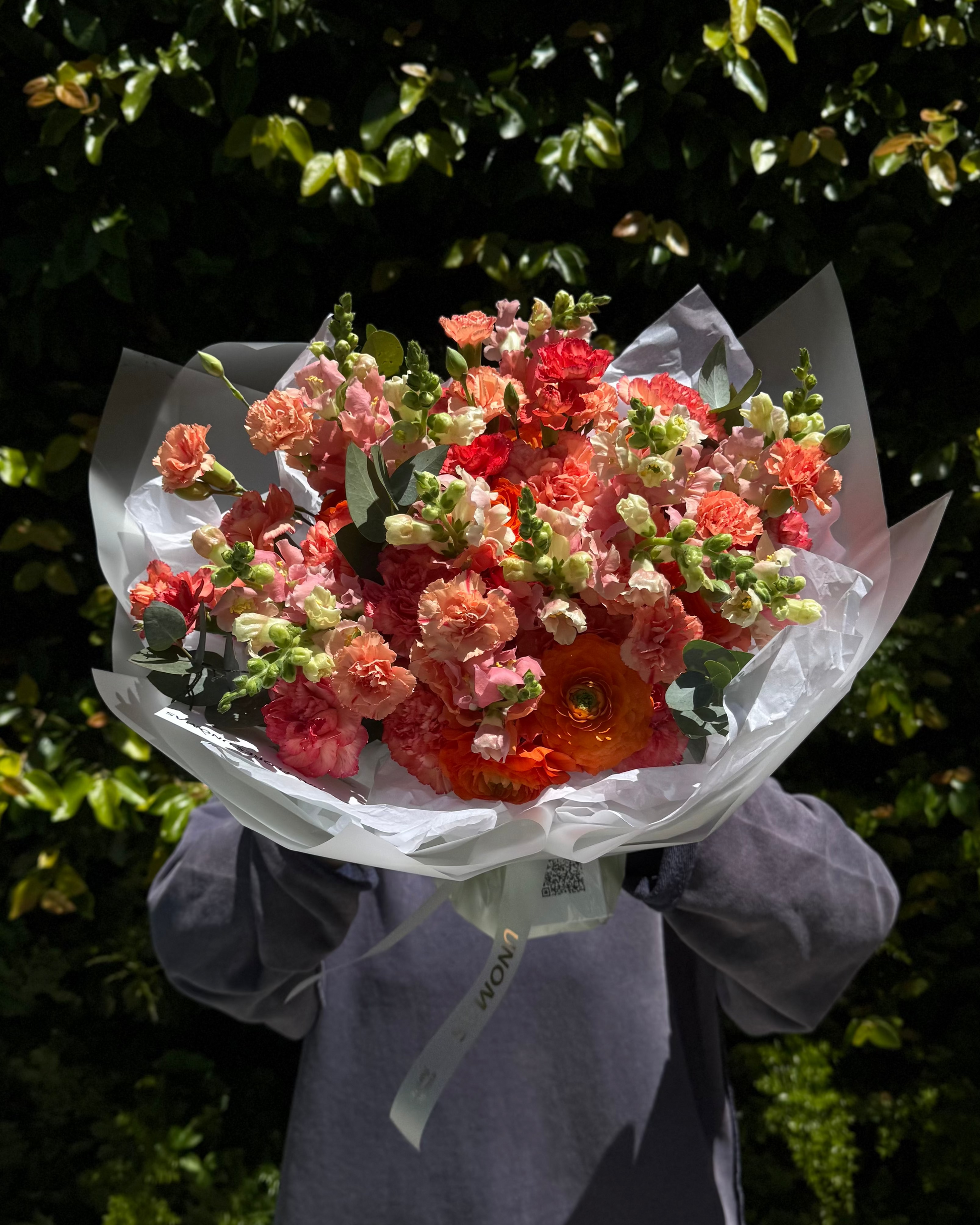 Person holding a bouquet of flowers against a green leafy background