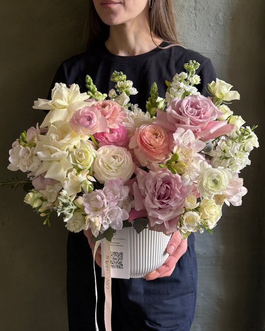 Person holding a large bouquet of flowers against a plain background