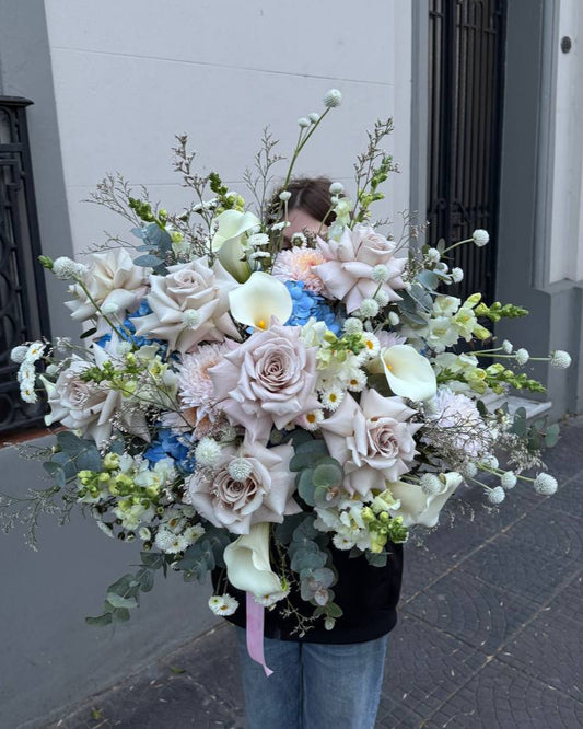 Person holding a large bouquet of flowers against a building exterior