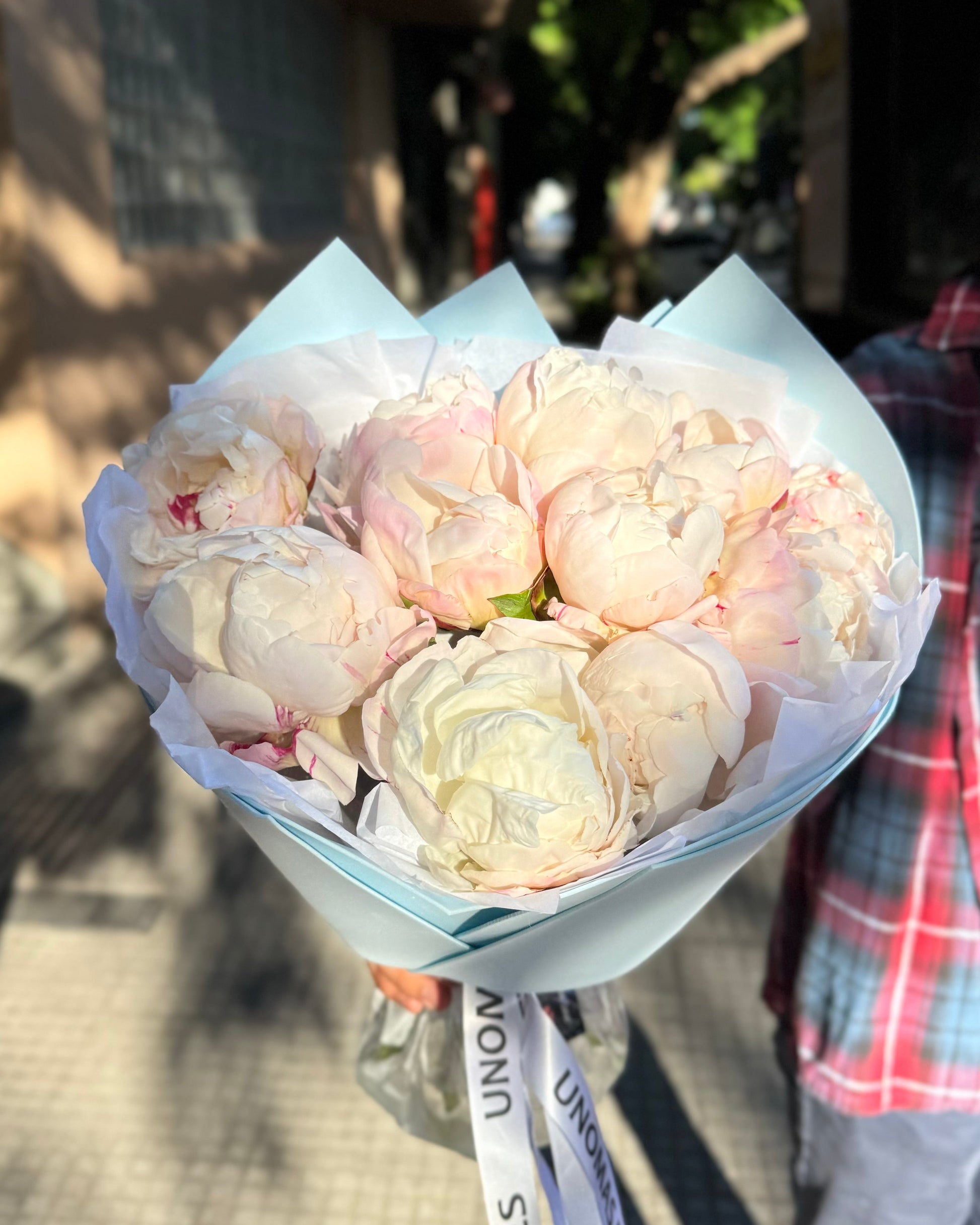 Bouquet of light pink flowers with a visible brand label in an outdoor setting