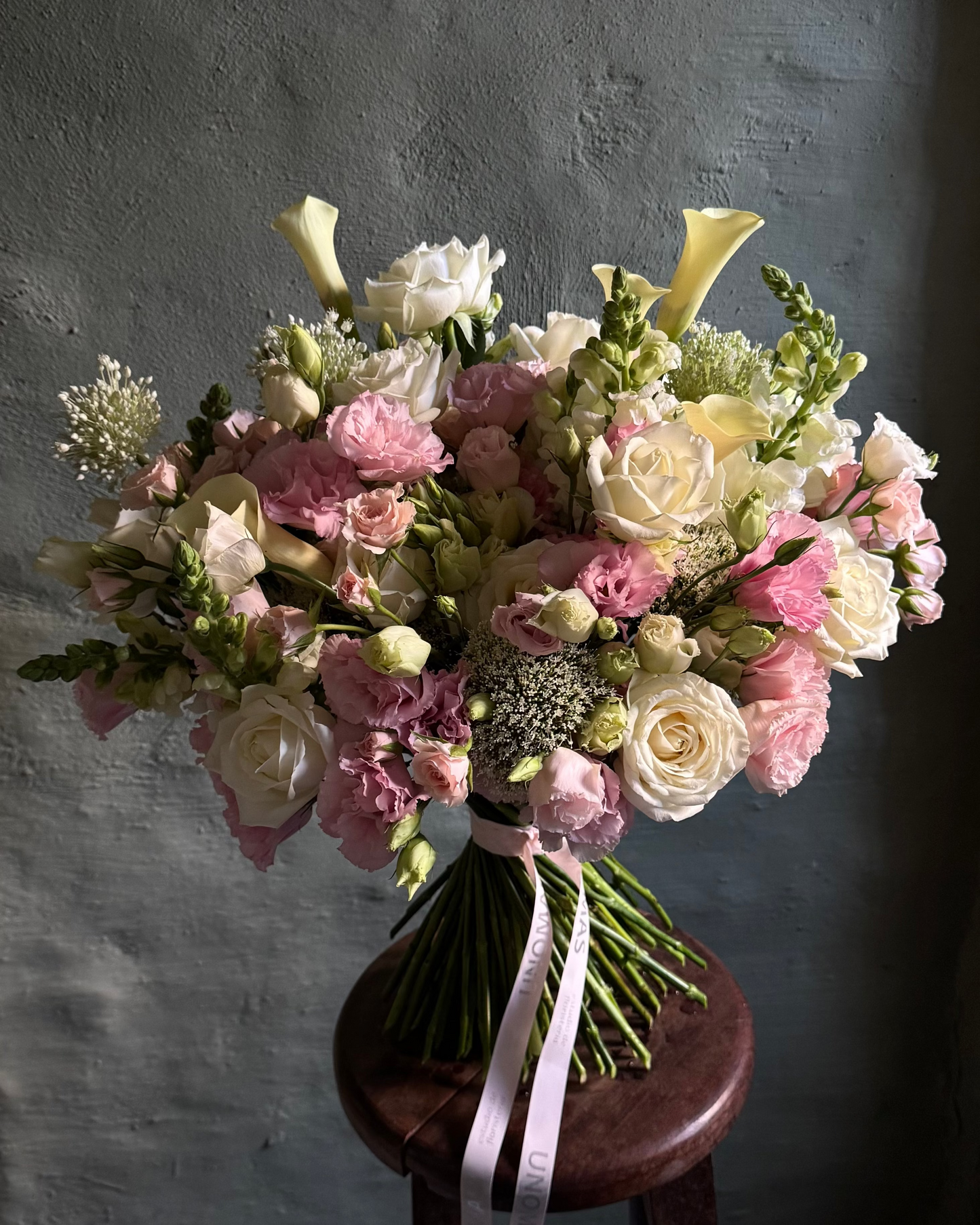 Bouquet of flowers on a wooden stool against a textured gray wall